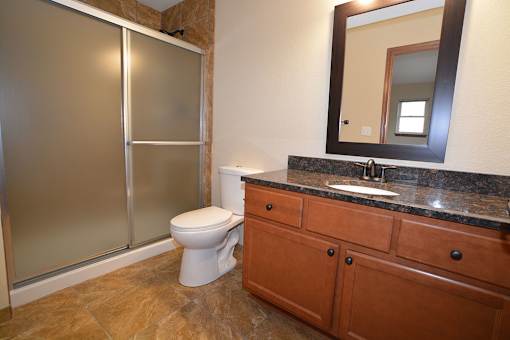 A bathroom with a toilet, sink, and mirror.