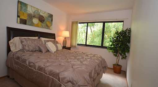 A bedroom with a bed, lamp, and a painting on the wall.