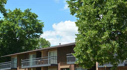 A building with a balcony and trees in front.
