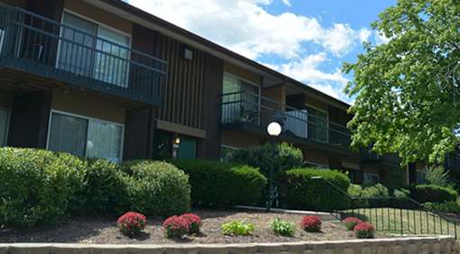 Apartment building with a black fence and bushes in front.