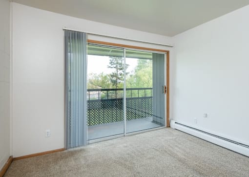 A room with a sliding glass door leading to a balcony.