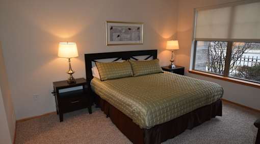 A bedroom with a bed, nightstands, and a window.