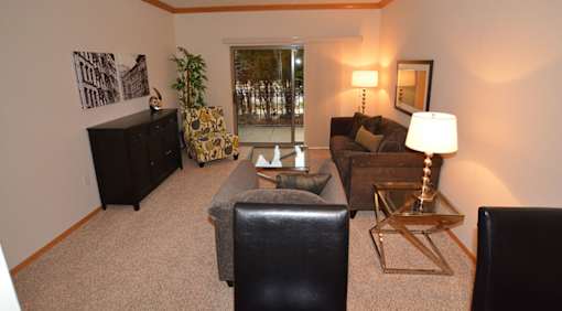 A living room with a black leather chair and a gold side table.