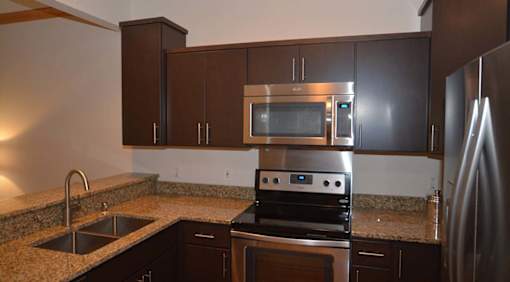 A kitchen with a stove, microwave, and refrigerator.