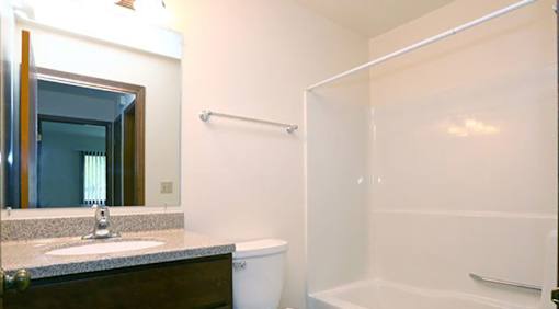 A bathroom with a sink, mirror, and bathtub.