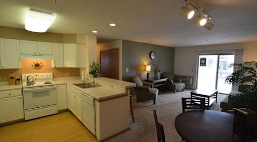 A kitchen with white appliances and wooden floors.