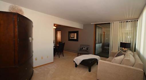 A living room with a brown couch and a black chair.