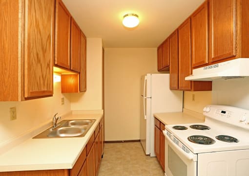 A kitchen with white appliances and wooden cabinets.