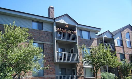 A large apartment building with balconies and trees in front.