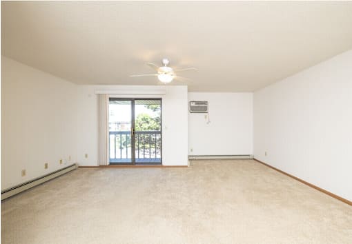 A room with a ceiling fan and a door leading to a balcony.
