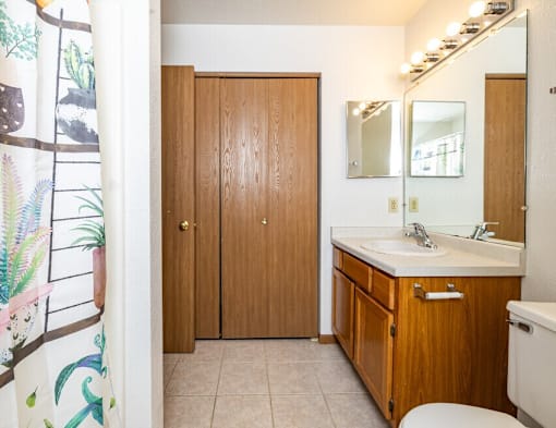 A bathroom with a toilet, sink, and wooden cabinets.