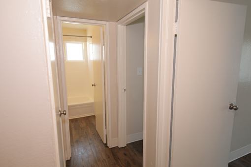 A hallway with white doors and a wooden floor.