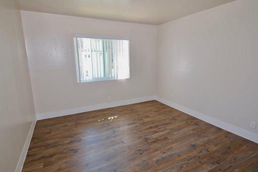 A room with wooden flooring and a window letting in light.