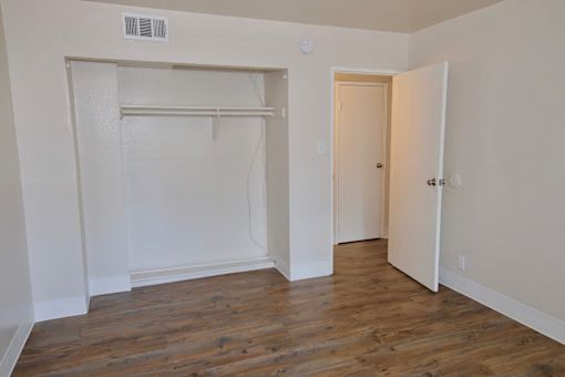 A room with a white door and a white closet with a white shelf.