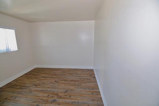 A room with wooden flooring and white walls.