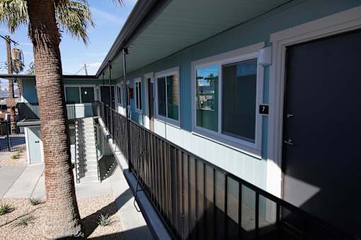 A balcony with a black railing and a palm tree in front of a house.