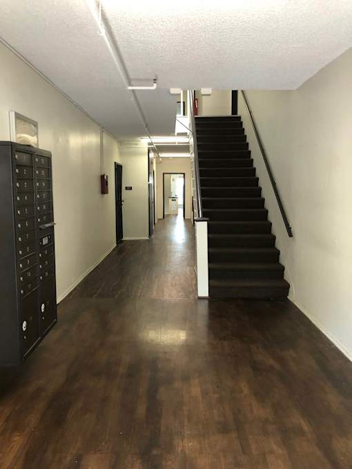 A long hallway with a staircase on the right and a door at the end.