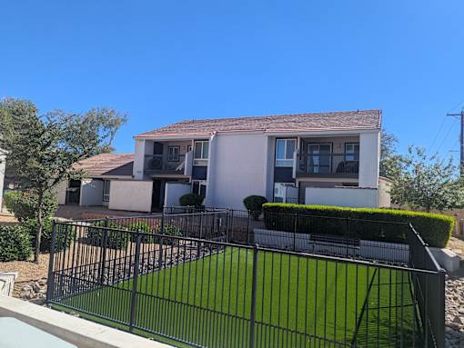 A house with a black fence and green lawn in front.