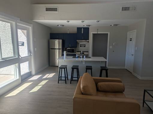 A kitchen with a refrigerator, microwave, and oven is visible.
