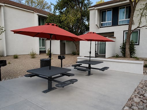 A red umbrella is on a table outside a house.