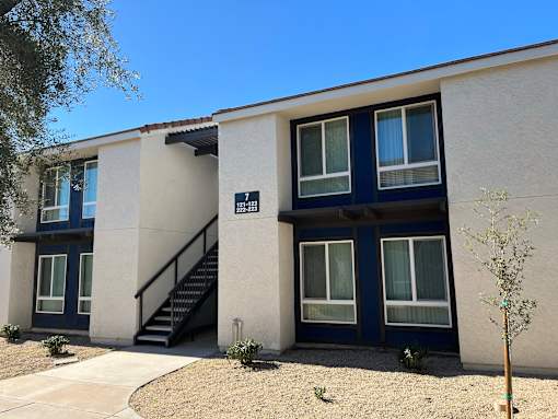 A building with a blue door and windows with white curtains.