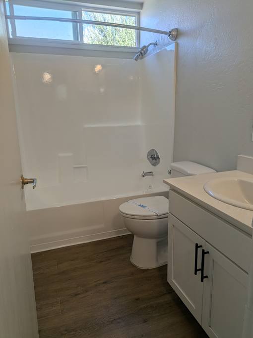 A white toilet sits in a bathroom next to a sink.