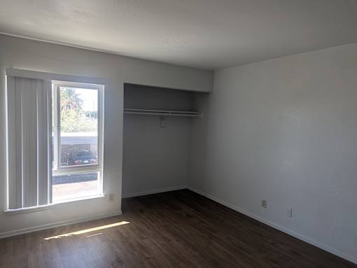 Empty room with a window and wooden floor.