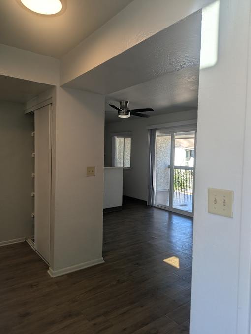 A room with a ceiling fan and wooden flooring.