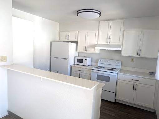 A kitchen with white appliances and cabinets.