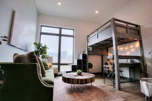 A room with a green couch, a wooden coffee table, and a bunk bed.