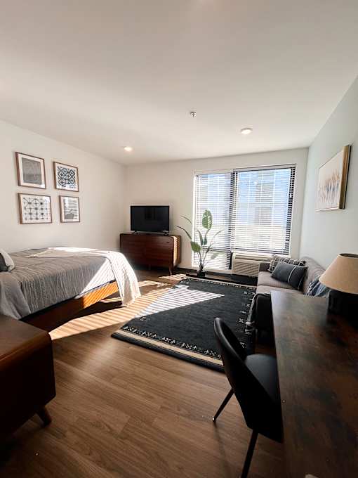 Studio apartment with bed desk and large window at The Traveler Apartments, Omaha, 68131