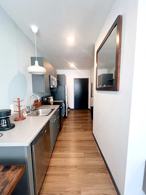 Galley kitchen with white countertops and pendant lighting at The Traveler Apartments, Omaha, Nebraska