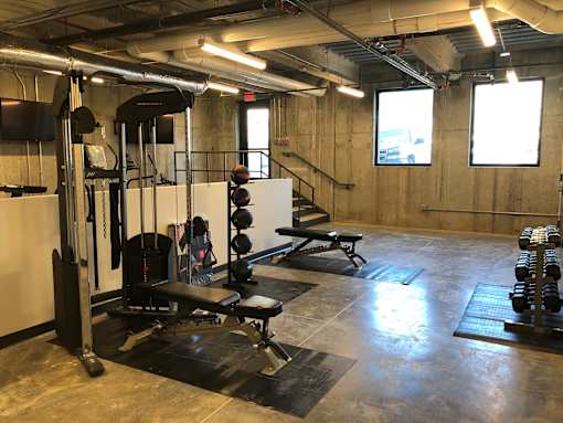 Fitness center with weight equipment and exercise mats at The Traveler Apartments, Omaha, Nebraska