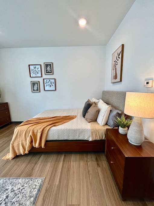 Bedroom with wood furniture and botanical wall art at The Traveler Apartments, Nebraska