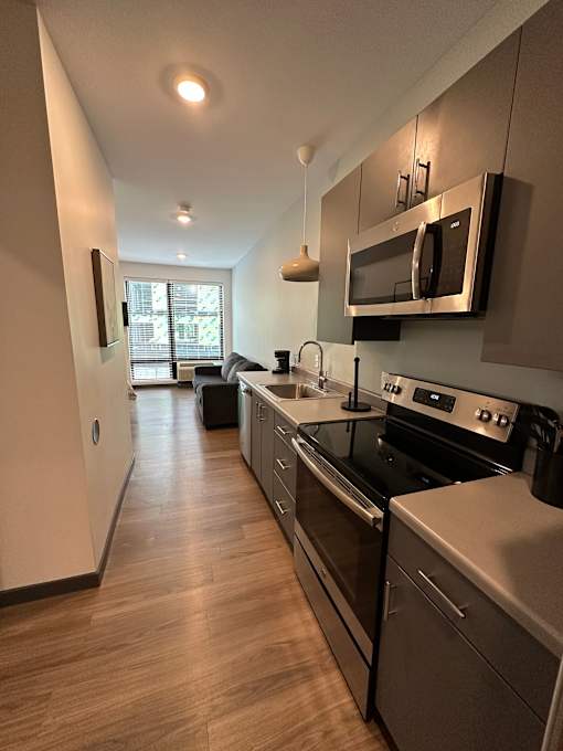 Open kitchen with stainless appliances and living space at The Traveler Apartments, Omaha