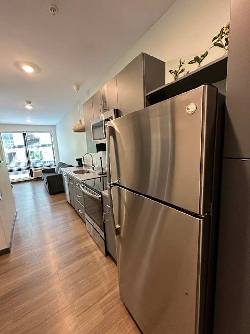Galley kitchen with stainless steel refrigerator and dishwasher at The Traveler Apartments, Nebraska