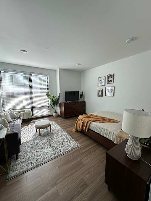 Studio apartment with bed seating area and hardwood floors at The Traveler Apartments, Omaha, NE