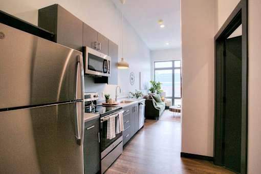 Narrow galley kitchen with modern gray cabinetry at The Traveler Apartments, Nebraska