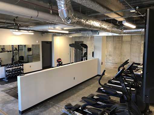 Fitness center with cardio machines and concrete walls at The Traveler Apartments, Nebraska, 68131