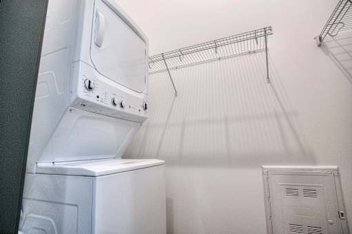 In unit stacked washer and dryer with wall mounted drying rack at The Traveler Apartments, Nebraska, 68131