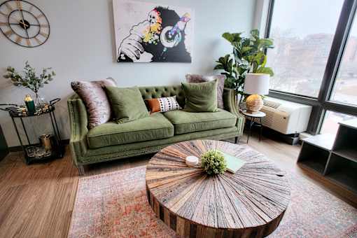Living room with green velvet sofa and round coffee table at The Traveler Apartments, Omaha, 68131