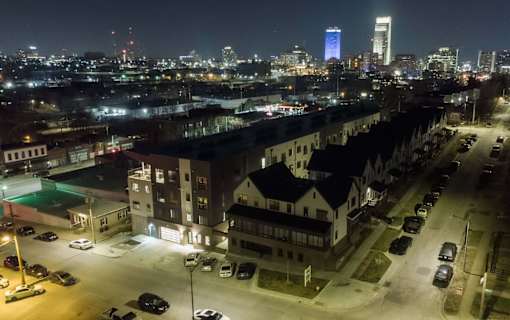 A cityscape at night with a brightly lit building in the distance.