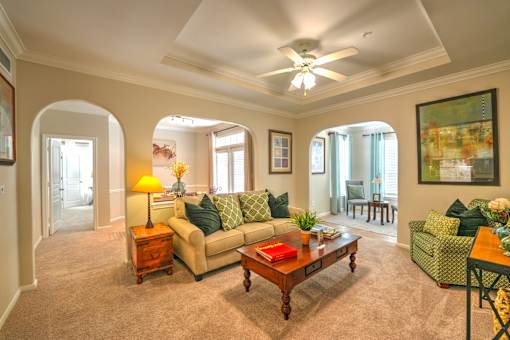 A living room with a couch, a coffee table, and a ceiling fan.