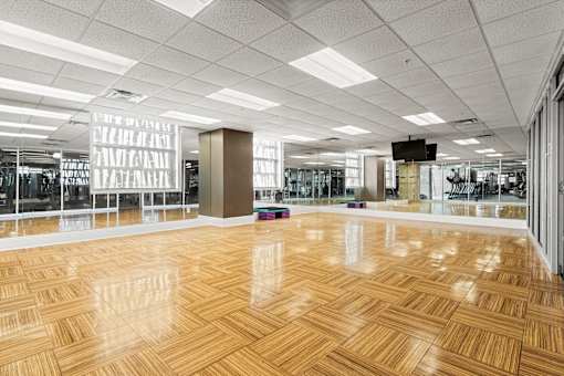 A spacious room with wooden flooring and a large mirror on the wall.
