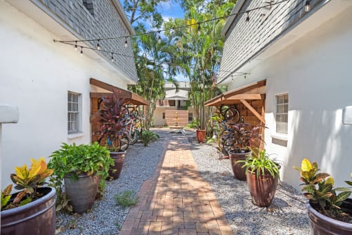 a courtyard with potted plants and a white building with a gray roof