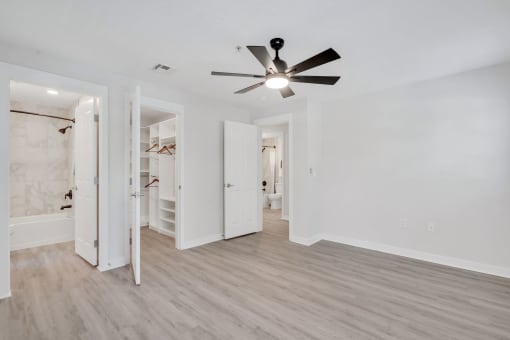 a bedroom with white walls and a ceiling fan