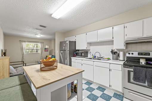A kitchen with white cabinets and a wooden island.