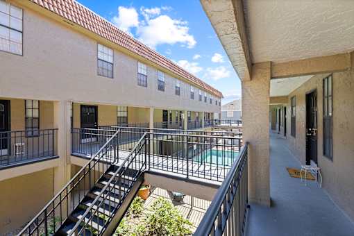 A balcony with a metal railing and a chair is visible.