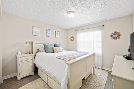 A bedroom with a bed, nightstand, and a window with curtains.