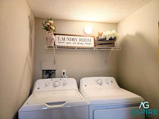 A small laundry room with two washing machines and a shelf above them.